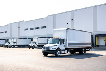 several box trucks parked at a freight facility