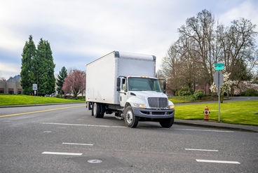 a box truck parked in the street in a rural neighborhood